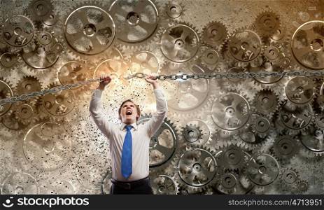 Powerful businessman. Young furious businessman breaking metal chain with hands