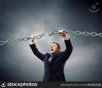 Powerful businessman. Young strong businessman tearing metal chain with hands