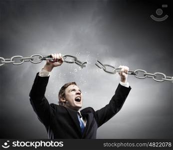 Powerful businessman. Young strong businessman tearing metal chain with hands