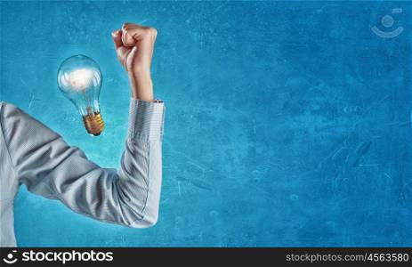 Powerful idea. Hand of business person showing power concept and glowing light bulb