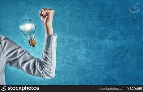 Powerful idea. Hand of business person showing power concept and glowing light bulb