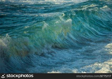 Powerful large turquoise colored waves crashing at Sennen Cove in Cornwall during late sunset