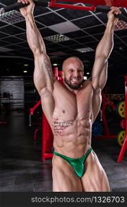 Powerful muscular man doing abs exercise on the horizontal bar