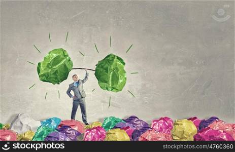 Powerlifter of great ideas. Businessman lifting in hand big crumpled ball of colorful paper as creativity sign