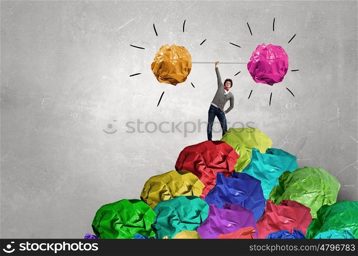 Powerlifter of great ideas. Businessman lifting in hand big crumpled ball of colorful paper as creativity sign