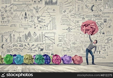 Powerlifter of great ideas. Man lifting in hand big crumpled ball of colorful paper as creativity sign