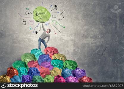 Powerlifter of great ideas. Man lifting in hand big crumpled ball of colorful paper as creativity sign