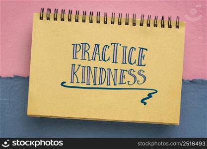 Practice kindness reminder - handwriting in a sketchbook against abstract paper landscape
