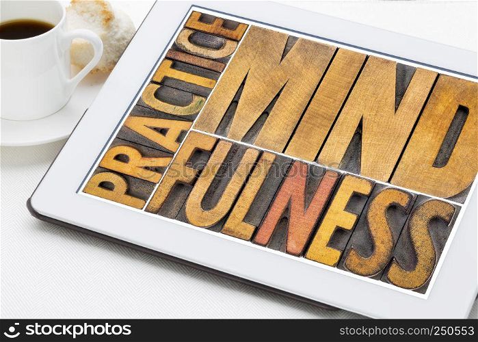 practice mindfulness word abstract - awareness concept - text in letterpress wood type on a digital tablet with coffee