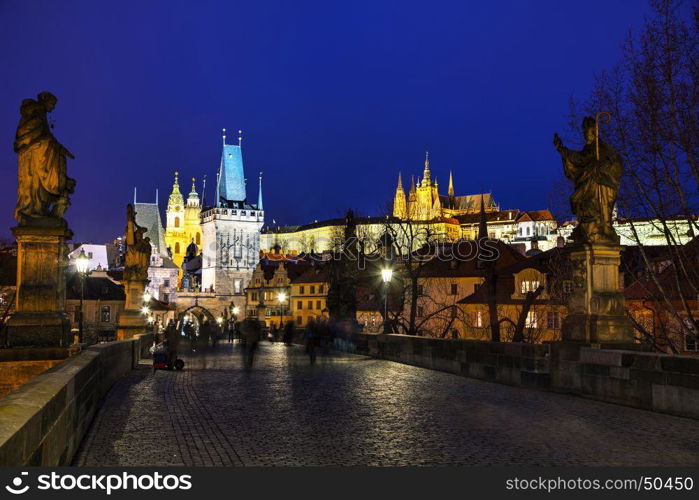 PRAGUE - MARCH 03: Charles bridge in the evening with people on March 03, 2017 in Prague. This famous historic bridge crosses the Vltava river and was constructed in the beginning of the 15th century.