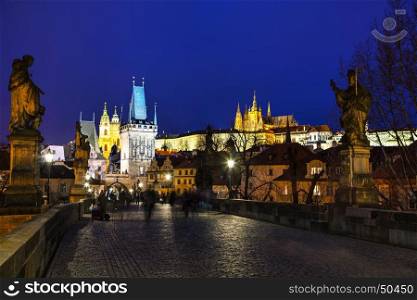 PRAGUE - MARCH 03: Charles bridge in the evening with people on March 03, 2017 in Prague. This famous historic bridge crosses the Vltava river and was constructed in the beginning of the 15th century.