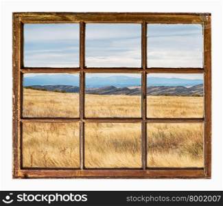 prairie with dry grass at Colorado foothills as seen through vintage, grunge, sash window with dirty glass