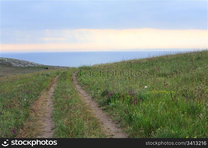 Prairies on evening summer sea coast and sun reflections in water