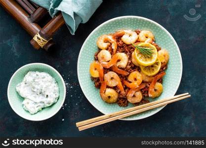 Prawns roasted on grill and boiled brown rice on plate. Grilled shrimps, prawns with rice. Seafood. Asian cuisine. Top view. Dark background