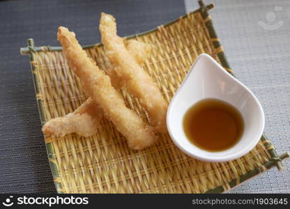 Prawns tempura with soy sauce on yellow bamboo plate. Seafood tempura dish of traditional asian cuisine