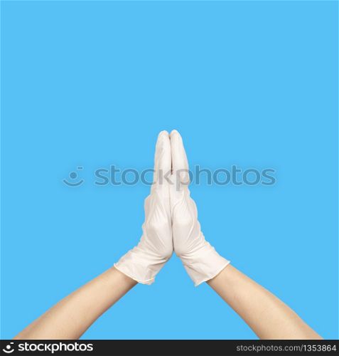 Pray or Namaste gesture in latex surgical gloved sign against blue background. Hand in a white latex glove isolated on white. Woman&rsquo;s hand gesture or sign isolated on white.. Hand in a white latex glove isolated on white. Woman&rsquo;s hand gesture or sign isolated on white.