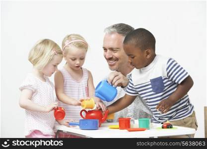 Pre School Children Enjoying Tea Party With Teacher
