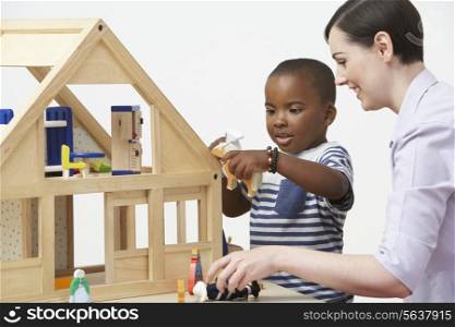 Pre-School Teacher And Pupil Playing With Wooden House