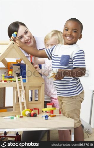 Pre-School Teacher And Pupils Playing With Wooden House