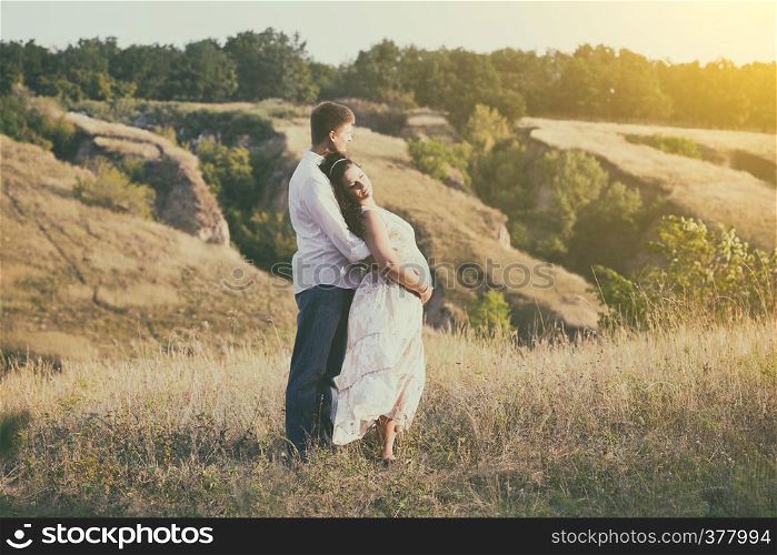 pregnancy - a man and a pregnant woman hugging outdoors