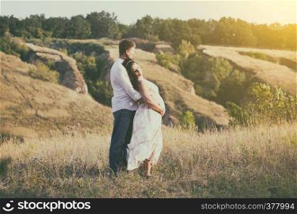 pregnancy - a man and a pregnant woman hugging outdoors