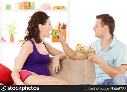 pregnancy and healthy eating concept - happy expecting parents at home