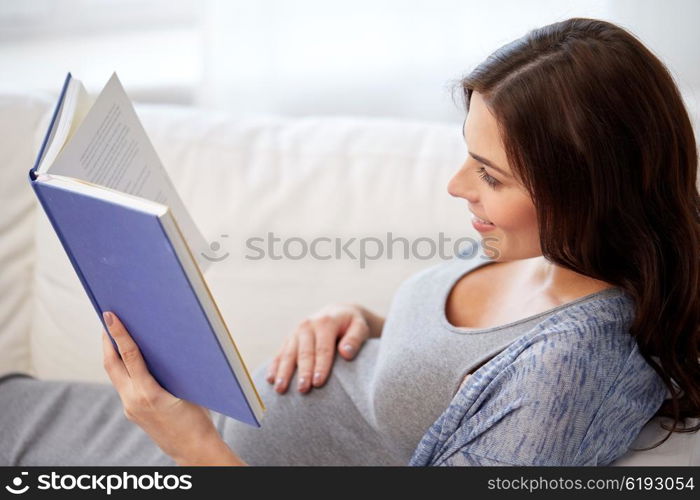 pregnancy and motherhood concept - smiling pregnant woman lying on sofa and reading book. happy pregnant woman reading book at home