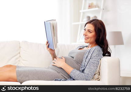 pregnancy and motherhood concept - smiling pregnant woman lying on sofa and reading book. happy pregnant woman reading book at home