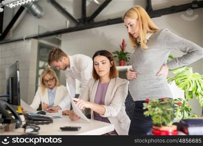 pregnancy and people concept - business team with papersin office. business team with papers in office