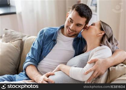 pregnancy and people concept - happy man hugging pregnant woman at home. man hugging pregnant woman at home