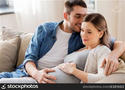 pregnancy and people concept - happy man hugging pregnant woman at home. man hugging pregnant woman at home