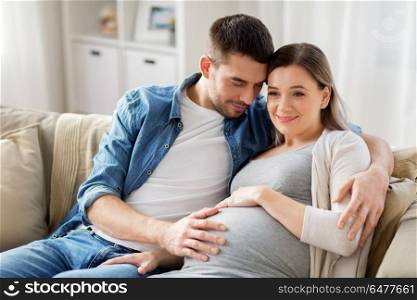 pregnancy and people concept - happy man hugging pregnant woman at home. man hugging pregnant woman at home. man hugging pregnant woman at home