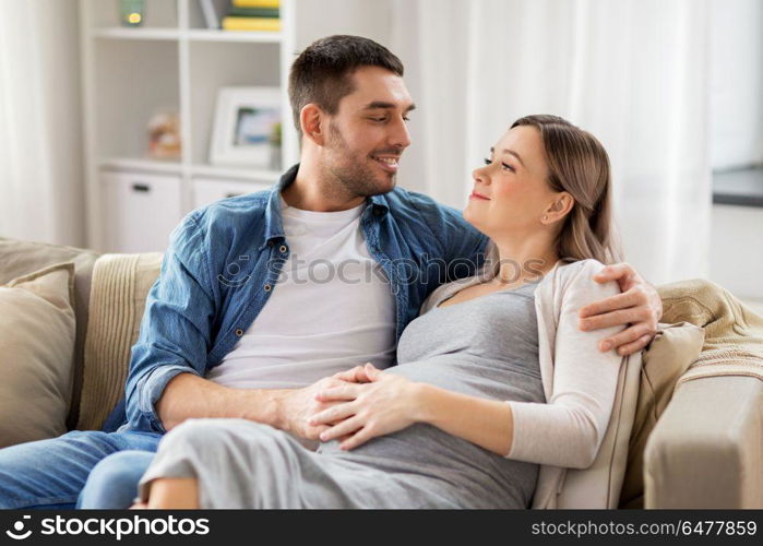 pregnancy and people concept - happy man hugging pregnant woman at home. man hugging pregnant woman at home. man hugging pregnant woman at home