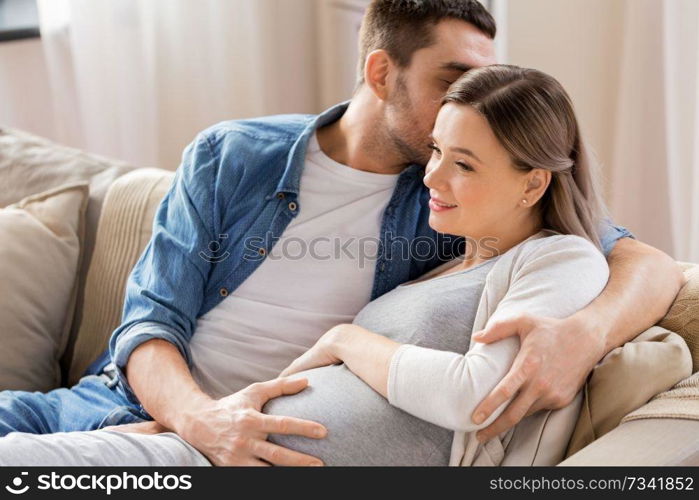 pregnancy and people concept - happy man hugging pregnant woman at home. man hugging pregnant woman at home