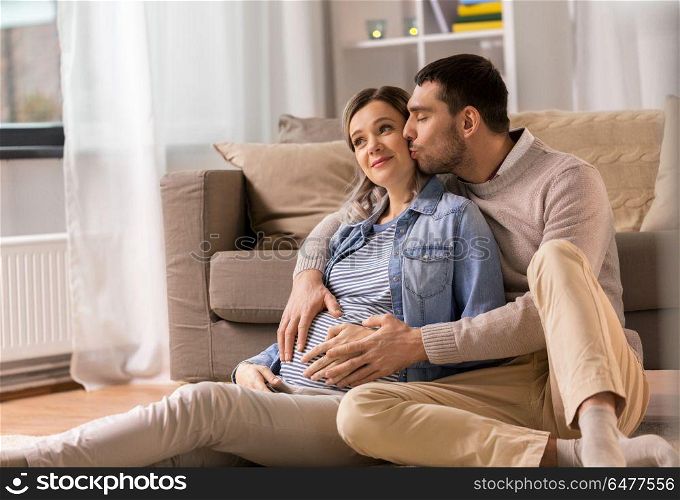 pregnancy and people concept - happy man kissing and hugging pregnant woman at home. man kissing and hugging pregnant woman at home. man kissing and hugging pregnant woman at home