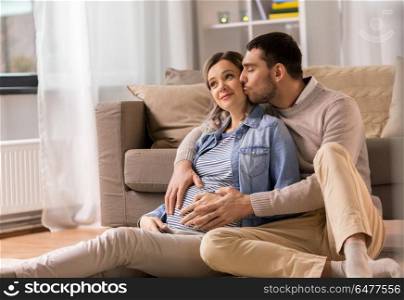 pregnancy and people concept - happy man kissing and hugging pregnant woman at home. man kissing and hugging pregnant woman at home. man kissing and hugging pregnant woman at home