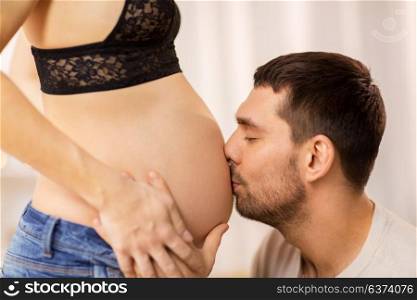 pregnancy and people concept - happy man kissing pregnant woman belly. happy man kissing pregnant woman belly