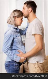 pregnancy and people concept - happy man with pregnant woman at home. happy man with pregnant woman at home. happy man with pregnant woman at home
