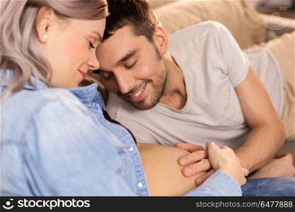 pregnancy and people concept - happy man with pregnant woman at home. happy man with pregnant woman at home. happy man with pregnant woman at home