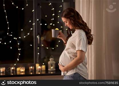 pregnancy and people concept - happy smiling pregnant woman drinking tea at home. happy pregnant woman drinking tea at home