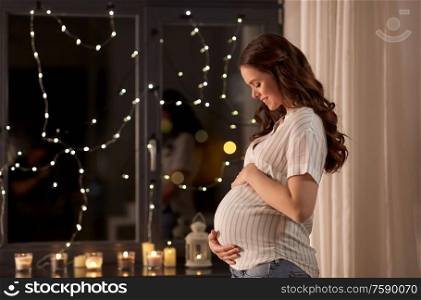 pregnancy and people concept - happy smiling pregnant woman looking out window at home. happy pregnant woman looking out window at home