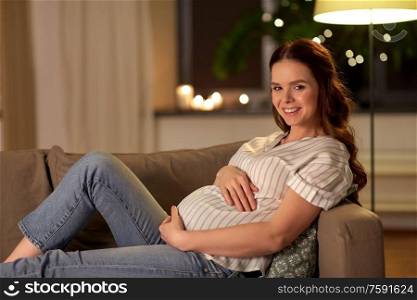 pregnancy and people concept - happy smiling pregnant woman on sofa at home. happy smiling pregnant woman on sofa at home
