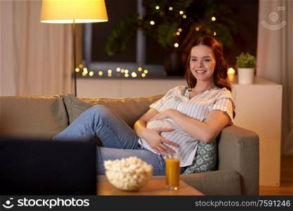 pregnancy and people concept - happy smiling pregnant woman on sofa watching tv at home. happy smiling pregnant woman watching tv at home