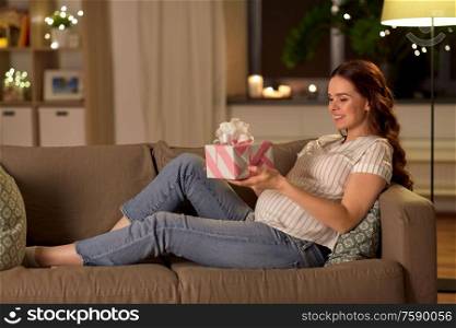 pregnancy and people concept - happy smiling pregnant woman with gift box on sofa at home. happy smiling pregnant woman with gift box at home