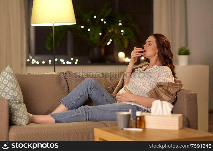 pregnancy and people concept - sick pregnant woman coughing on sofa at home. sick pregnant woman coughing at home