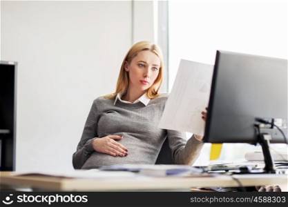 pregnancy, business and work concept - pregnant businesswoman sitting at office table and reading papers