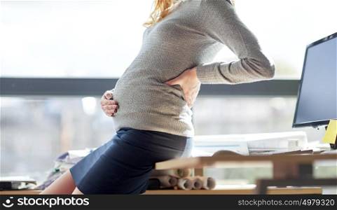 pregnancy, business, work and people concept - pregnant businesswoman sitting on table at office. pregnant businesswoman sitting on table at office