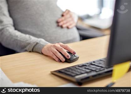 pregnancy, business, work and technology concept - close up of pregnant businesswoman with computer at office table. pregnant businesswoman with computer at office