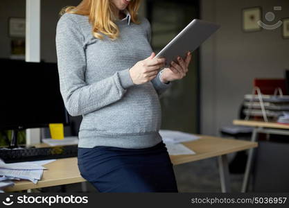 pregnancy, business, work and technology concept - close up of pregnant businesswoman with tablet pc computer at office. pregnant businesswoman with tablet pc at office