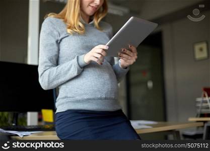 pregnancy, business, work and technology concept - close up of pregnant businesswoman with tablet pc computer at office. pregnant businesswoman with tablet pc at office
